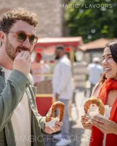 two young people standing and talking while eating