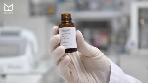 Lab technician holding Tobacco Essence flavor concentrate, matched to the tobacco product category