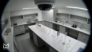 Flavor development laboratory with glassware, flasks, pipettes, and a ceiling security camera, where authentic shisha flavors are tested